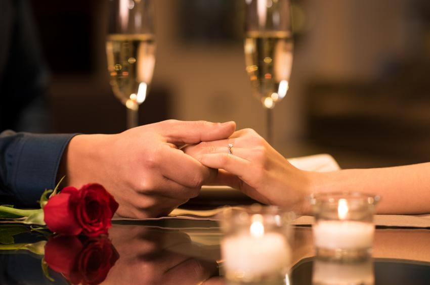 Paar hält sich an den Händen - Heiratsantrag im Restaurant 