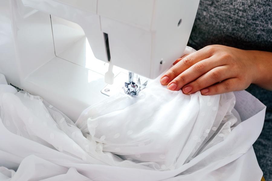 Hochzeitskleid wird mit einer Nähmaschine bearbeitet - nachhaltige Hochzeit