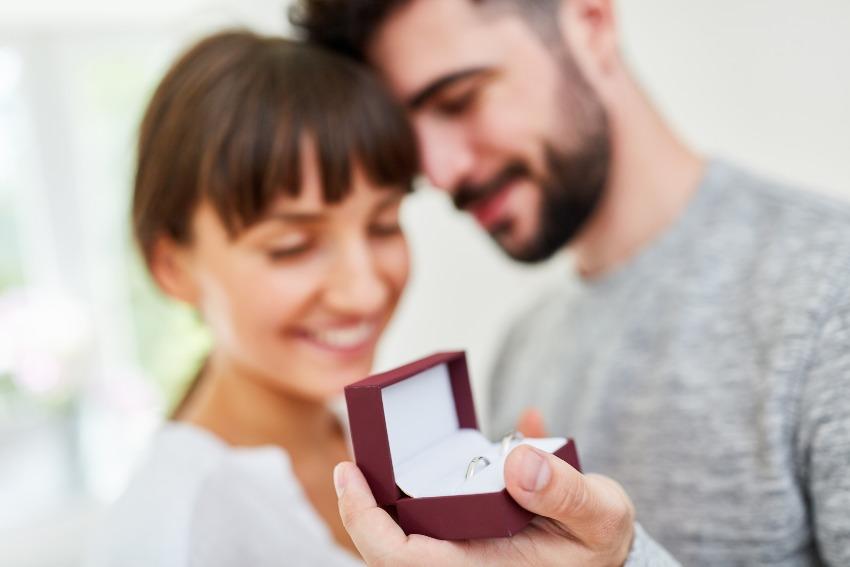 Junges Paar, Mann hält Kästchen mit Verlobungsring in der Hand - Heiratsantrag zu Ostern