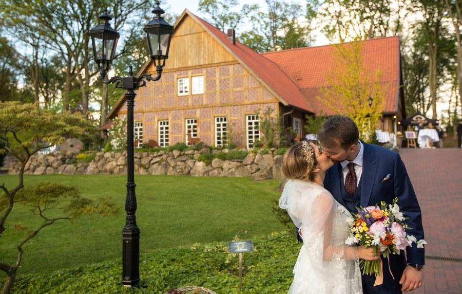 Brautpaar küsst sich, im Hintergrund ein Bauernhof