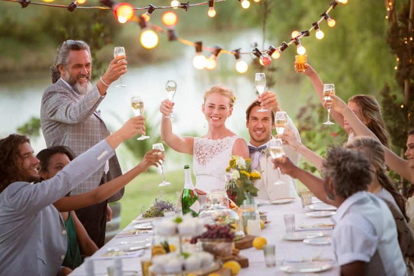 Kleine Hochzeitsgesellschaft am Tisch in einem Garten - 